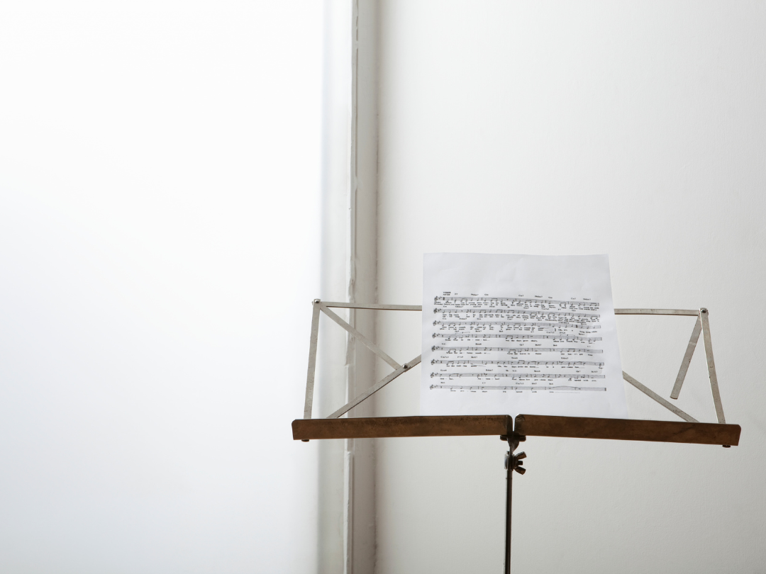 A single music stand with sheet music in a bright, naturally-lit room, capturing calm focus and the simplicity of practice.